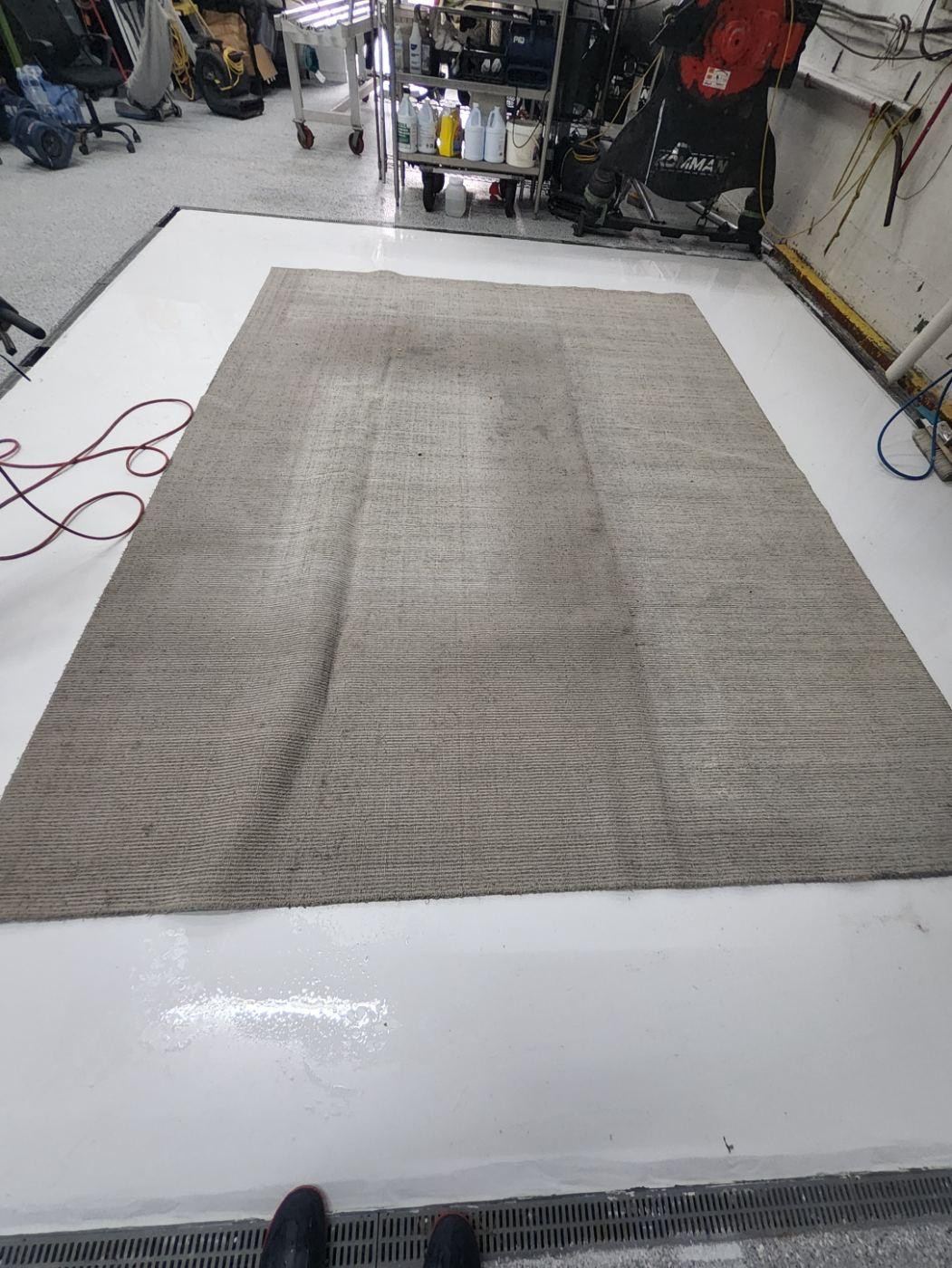 Gray area rug with a dark worn patch down the middle, before cleaning